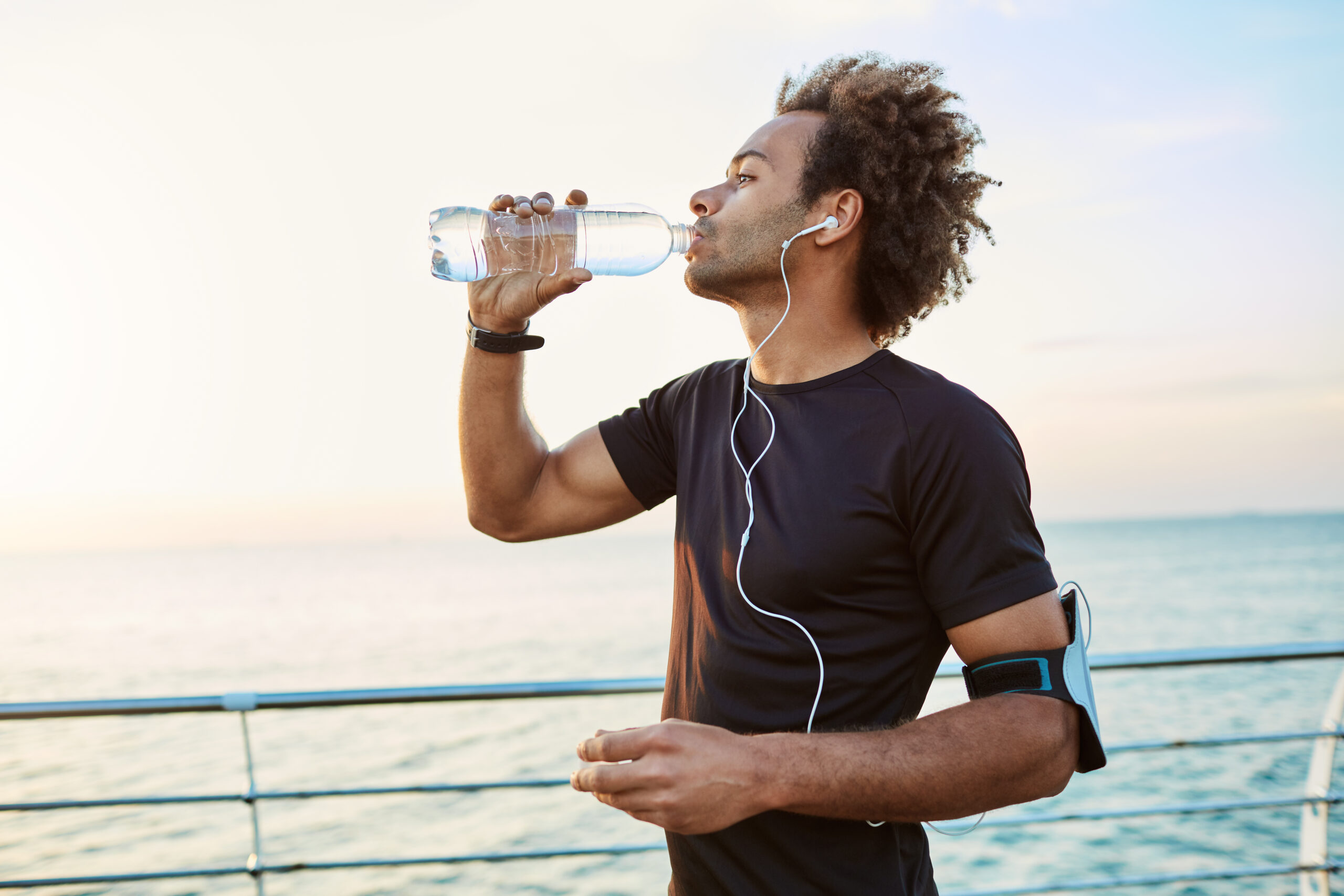 sportivo-snello-e-giovane-che-si-rinfresca-bevendo-acqua-dalla-bottiglia-di-plastica-alla-luce-del-sole-del-mattino-ascoltando-le-sue-canzoni-preferite-mentre-fa-jogging bicarbonato